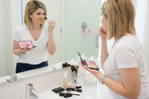 close up in mirror of applying everyday makeup routine in bathroom